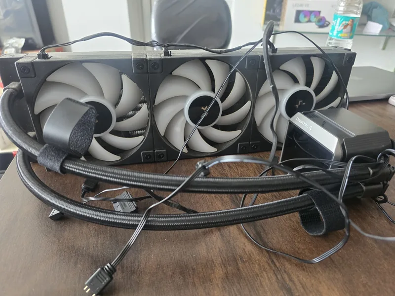 A DeepCool liquid CPU cooler with its radiator, fans, pump and cables laid out before RMA packing